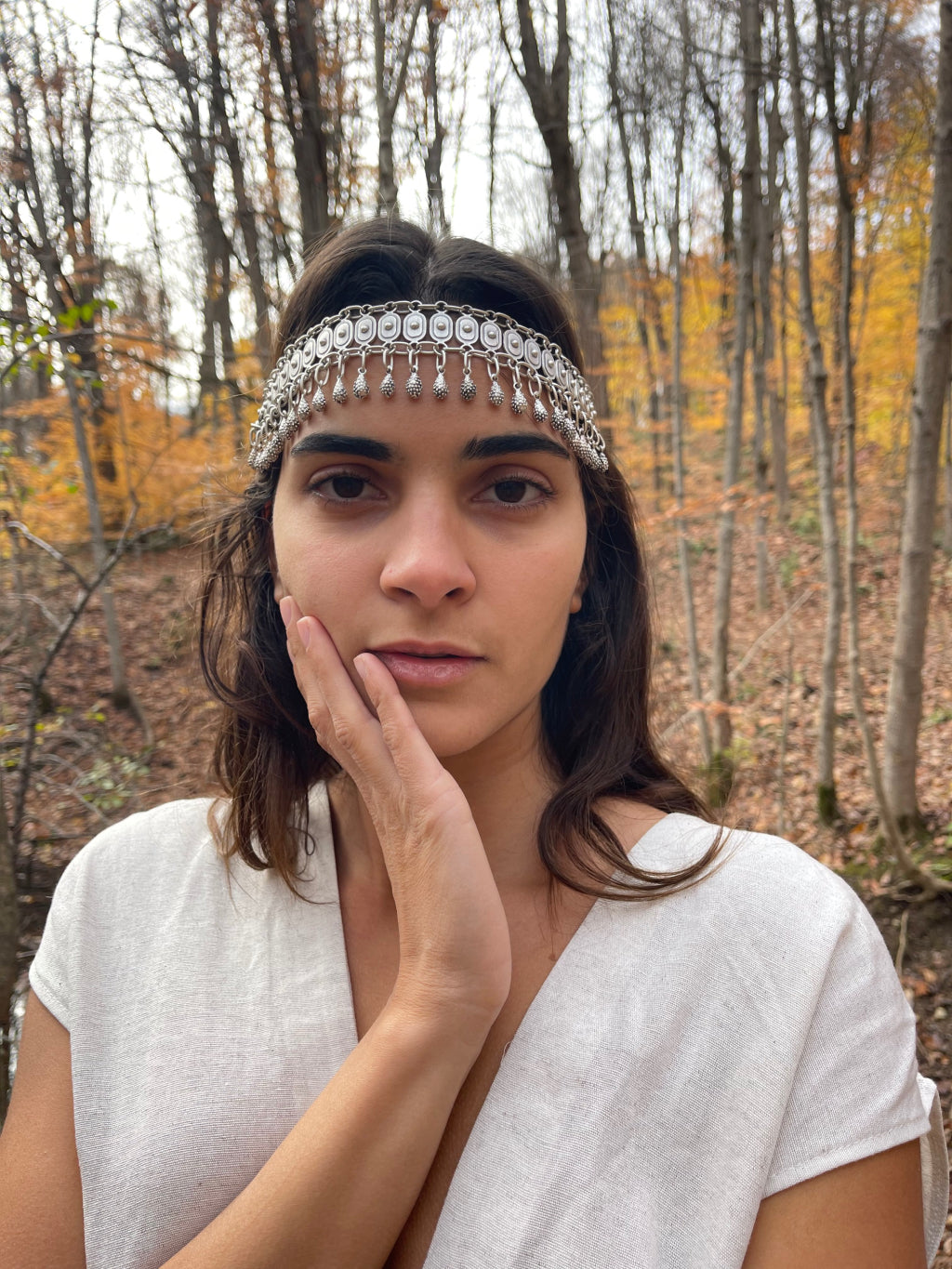 Goddess Warrior Head Chain - Elegant metal headpiece adorned with intricate patterns, complementing the model's natural beauty amidst the autumn-hued forest backdrop.