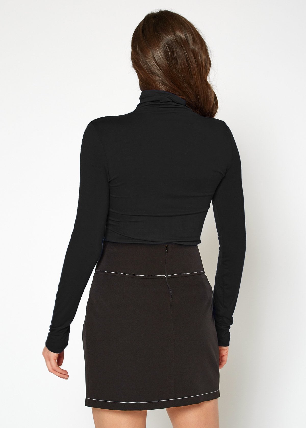 Women's long sleeve black turtleneck top with fitted design, showcasing the model's long brown hair from behind.