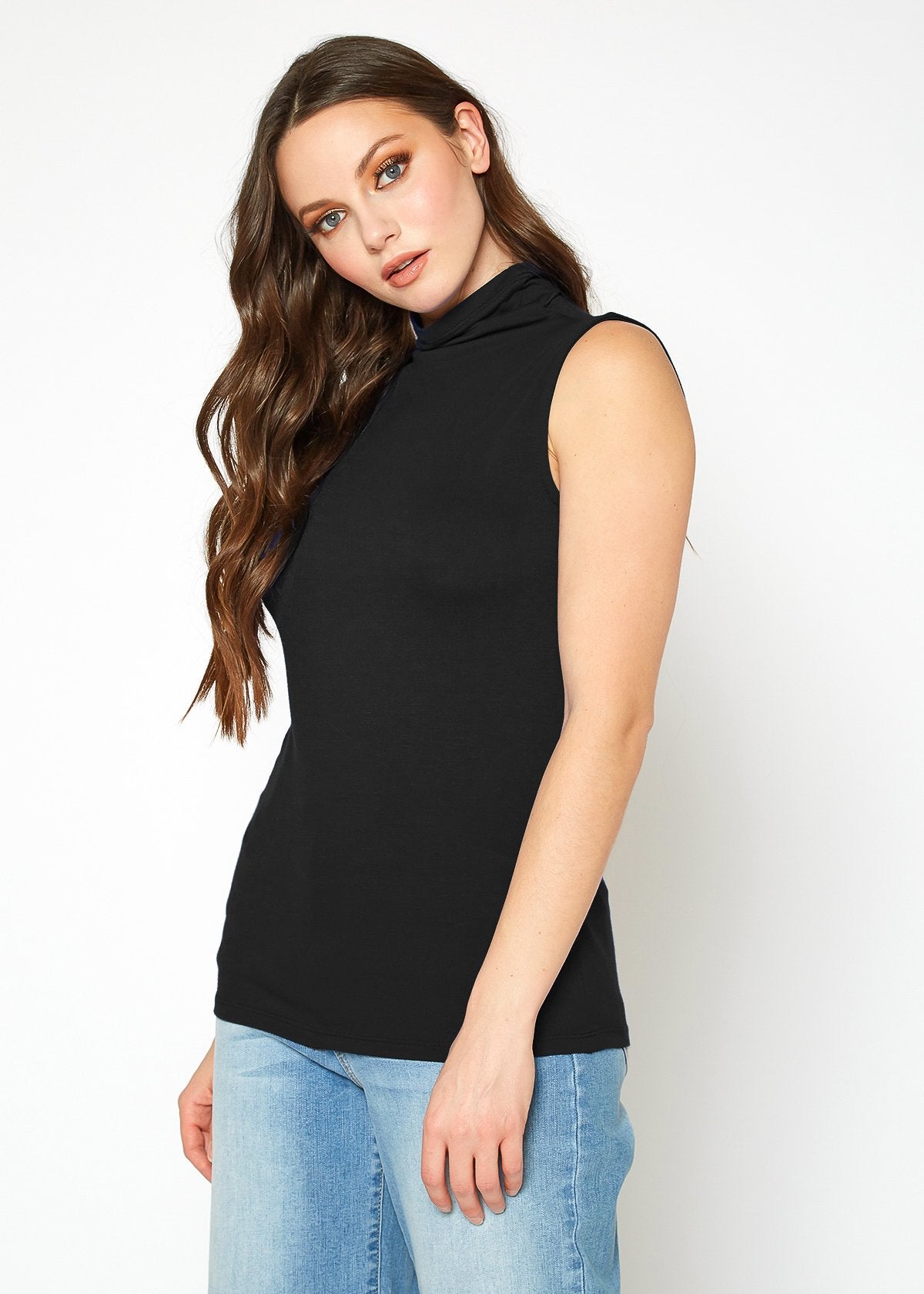 Sleeveless black turtleneck top on attractive female model with long wavy brown hair