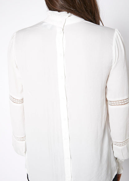 Elegant women's white long-sleeve mock neck top with delicate eyelet detailing on the sleeves, featured in the image.