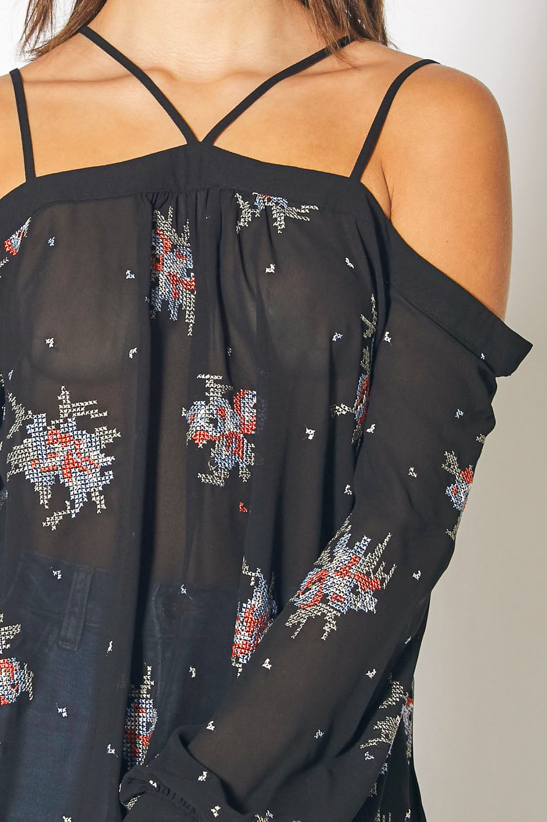 Off-shoulder embroidered floral print blouse in black, featuring criss-cross straps and a flowy, loose fit.