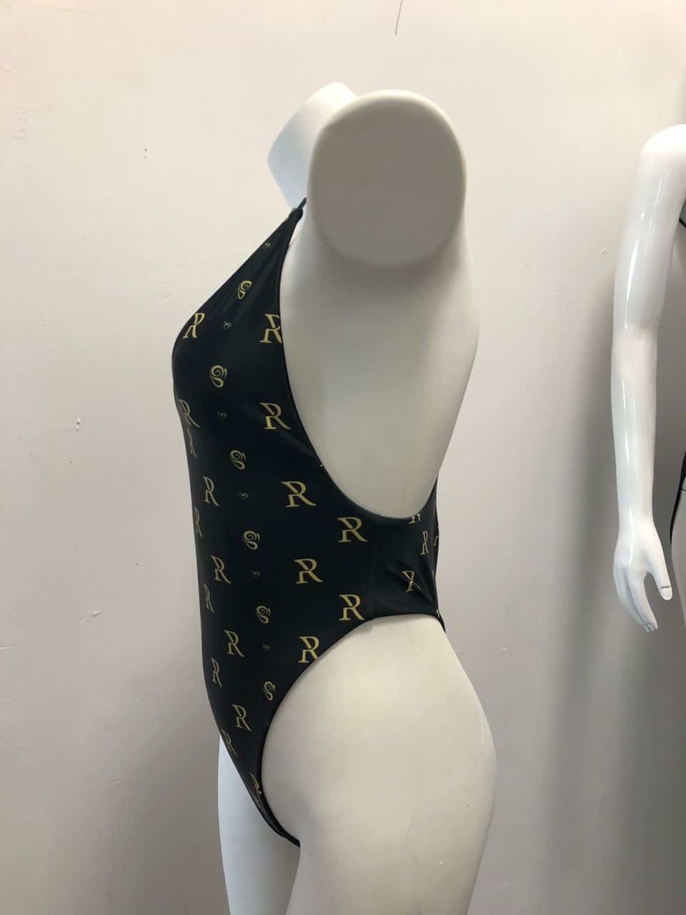 Rose Paulino Official Cross Swimsuit - Black and gold patterned women's one-piece swimsuit displayed on a mannequin in a fashion shop.