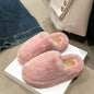 Cozy pink fuzzy round toe slippers on a white surface, with a denim background.