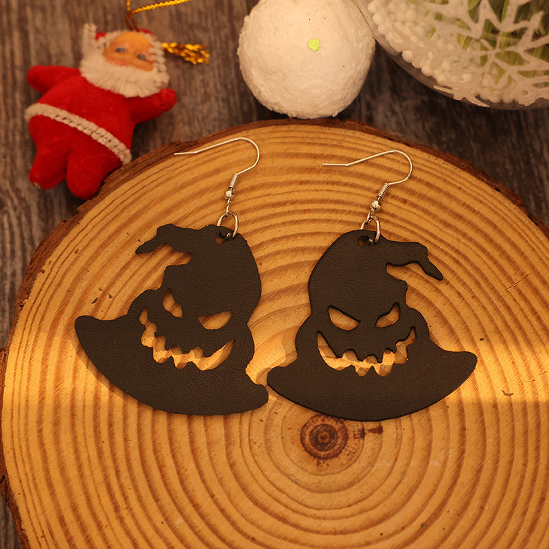 Spooky Halloween hat-shaped earrings made of black PU leather, displayed on a wooden surface with festive decorations.