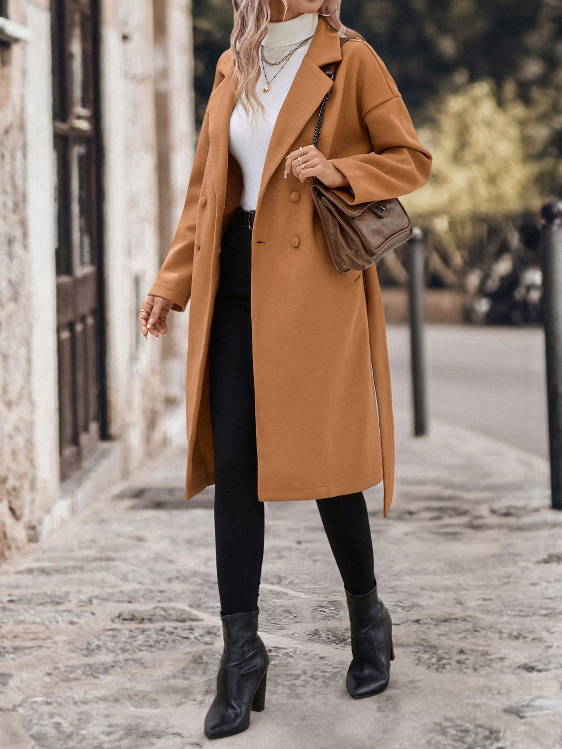 Chic camel-colored wool coat with dropped shoulders and a tie waist, worn by a fashionable woman on a city street