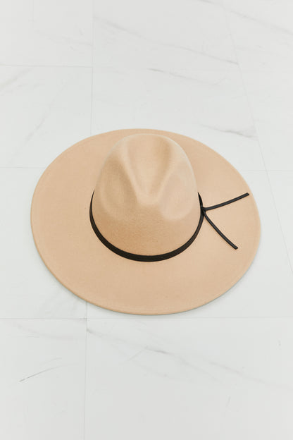 Stylish beige fedora hat with black band on light marble background