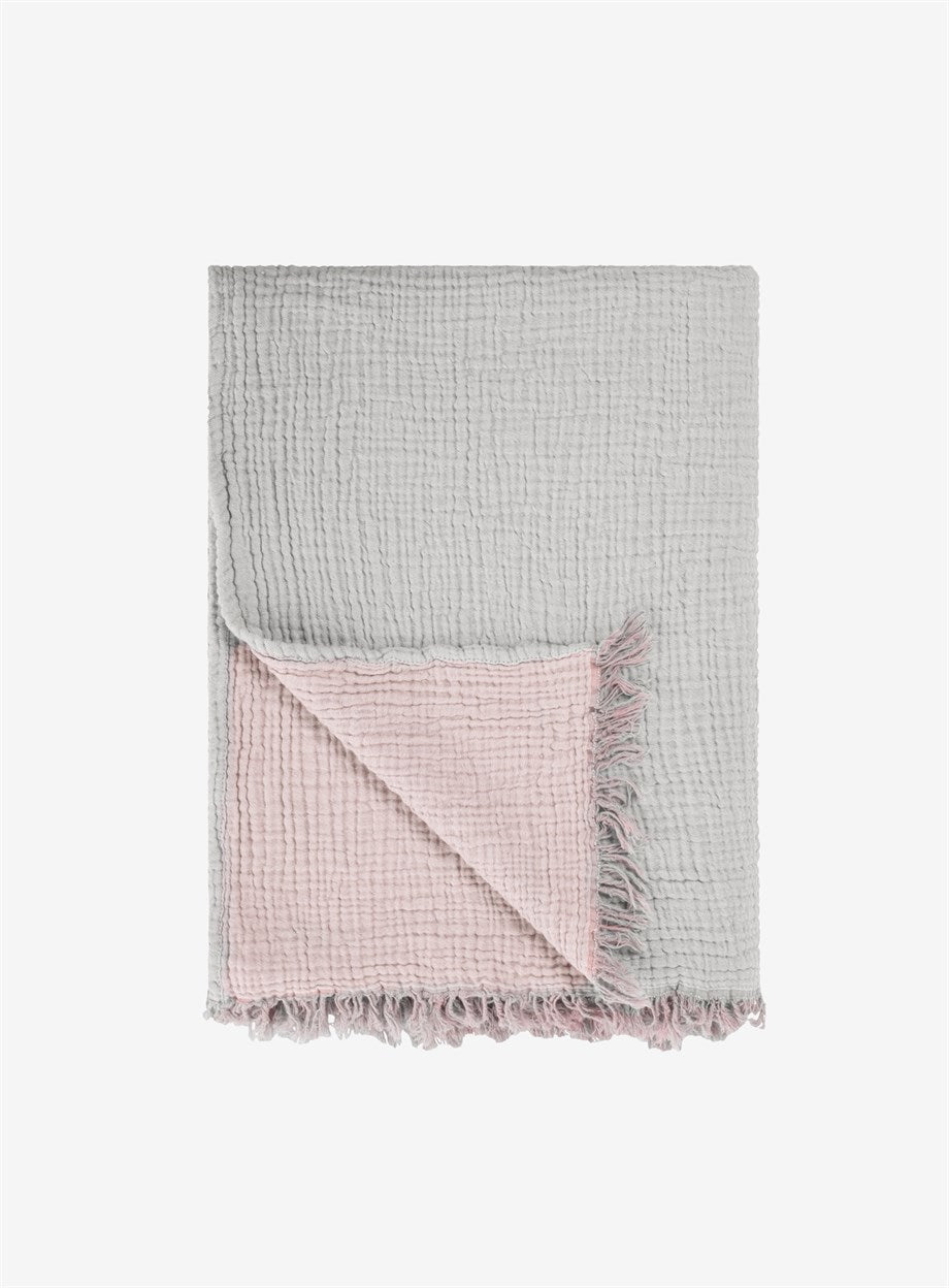 Soft, gray cotton throw blanket with a pink accent panel, perfect for cozy comfort on the couch.