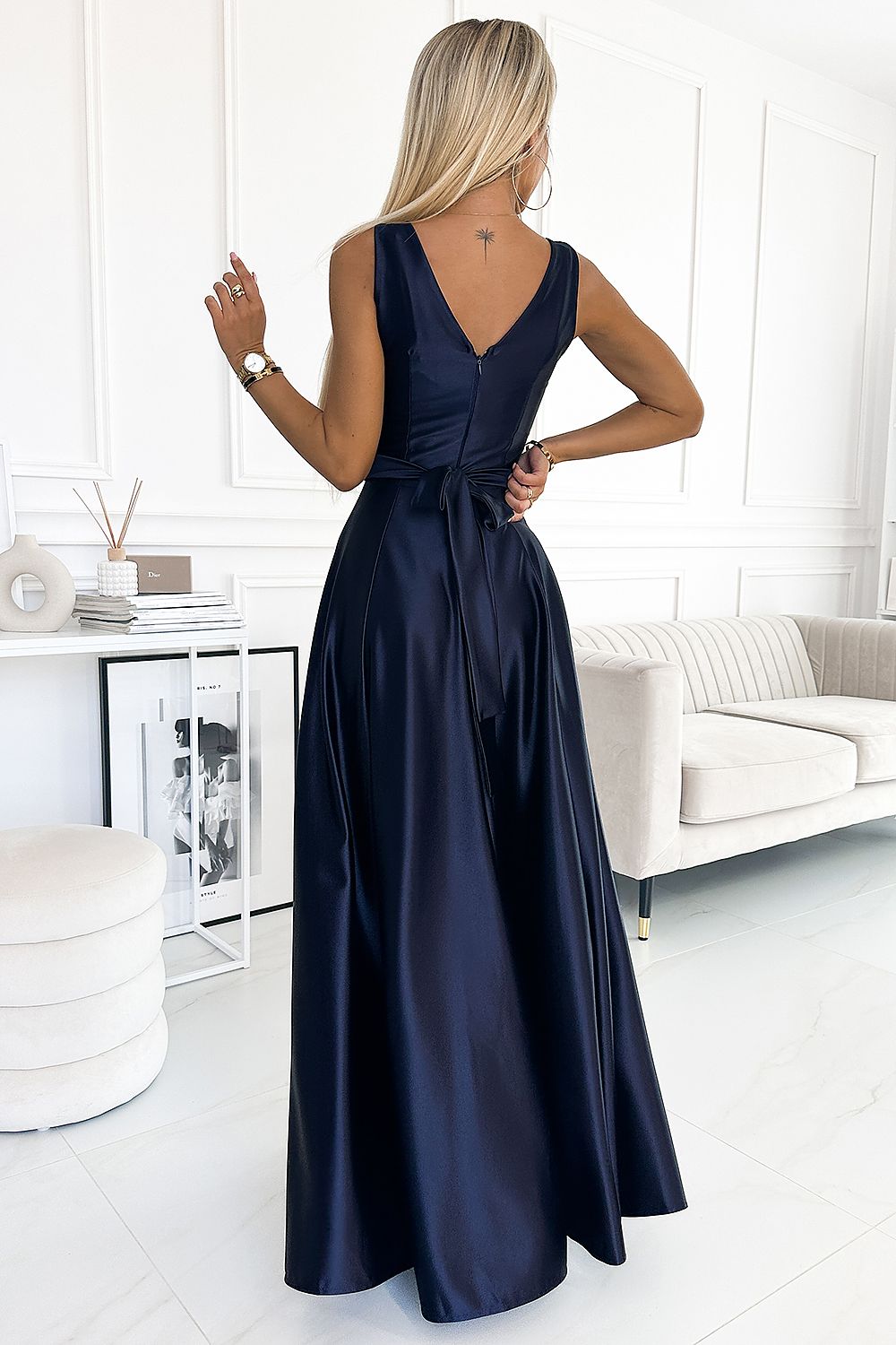 Elegant navy blue formal dress with v-neck and floor-length skirt, displayed in a clean, modern interior setting.