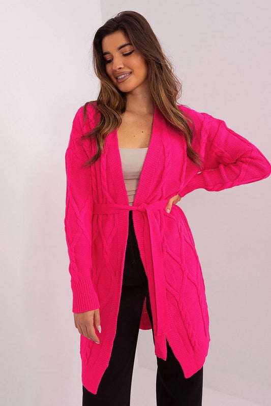 Vibrant pink knit cardigan with cable pattern, worn by a smiling young woman against a plain white background.