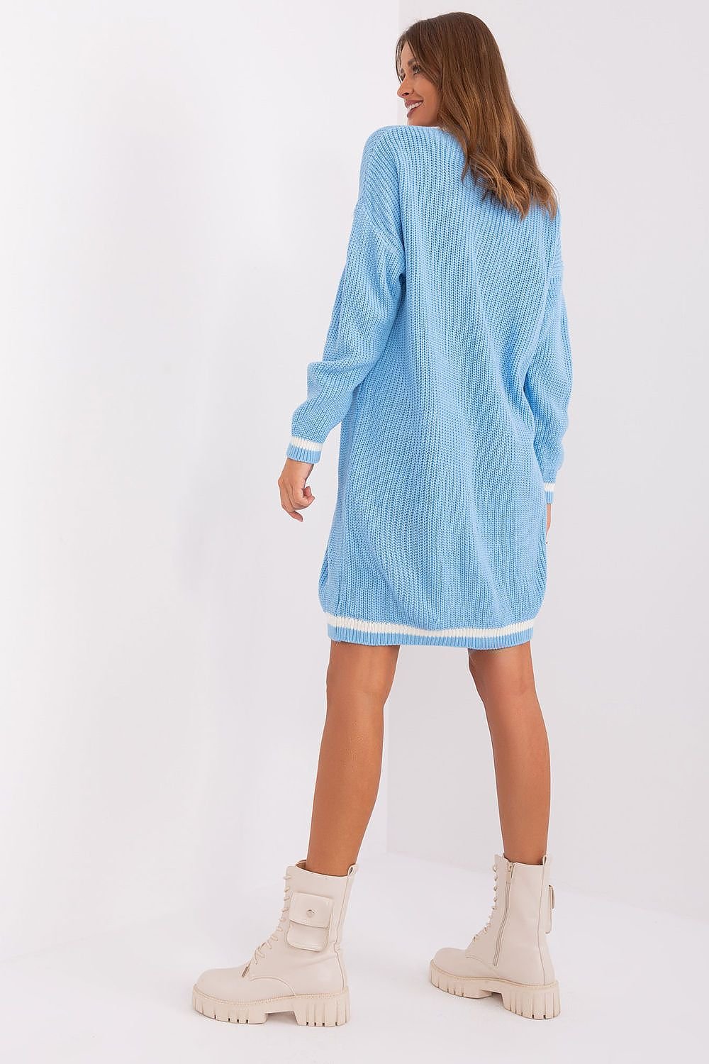 Cozy light blue knit dress with ribbed detailing, featuring a long sleeve design and relaxed silhouette. The model is wearing chunky white platform boots, completing the casual yet stylish ensemble.