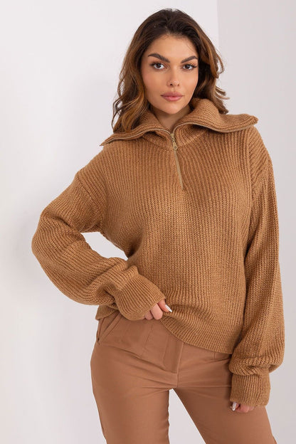 Cozy camel-colored turtleneck sweater with ribbed texture, worn by a young brunette woman against a plain white background.