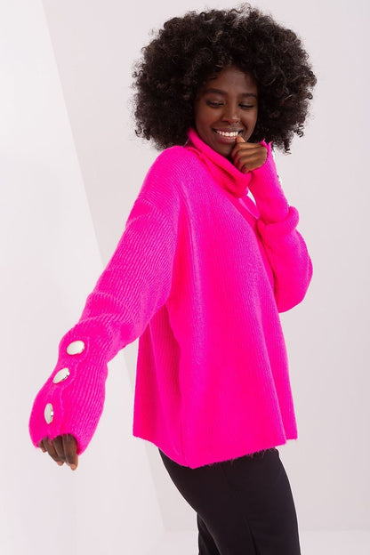 Vibrant pink turtleneck sweater with oversized sleeves and buttons, worn by a cheerful woman with curly black hair against a plain white background.