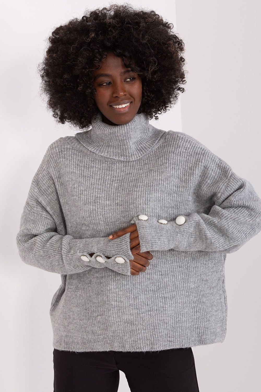 Cozy gray turtleneck knit sweater with decorative buttons on model with voluminous curly dark hair