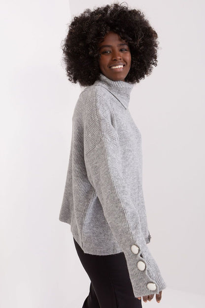 Curly-haired woman in gray turtleneck sweater, smiling