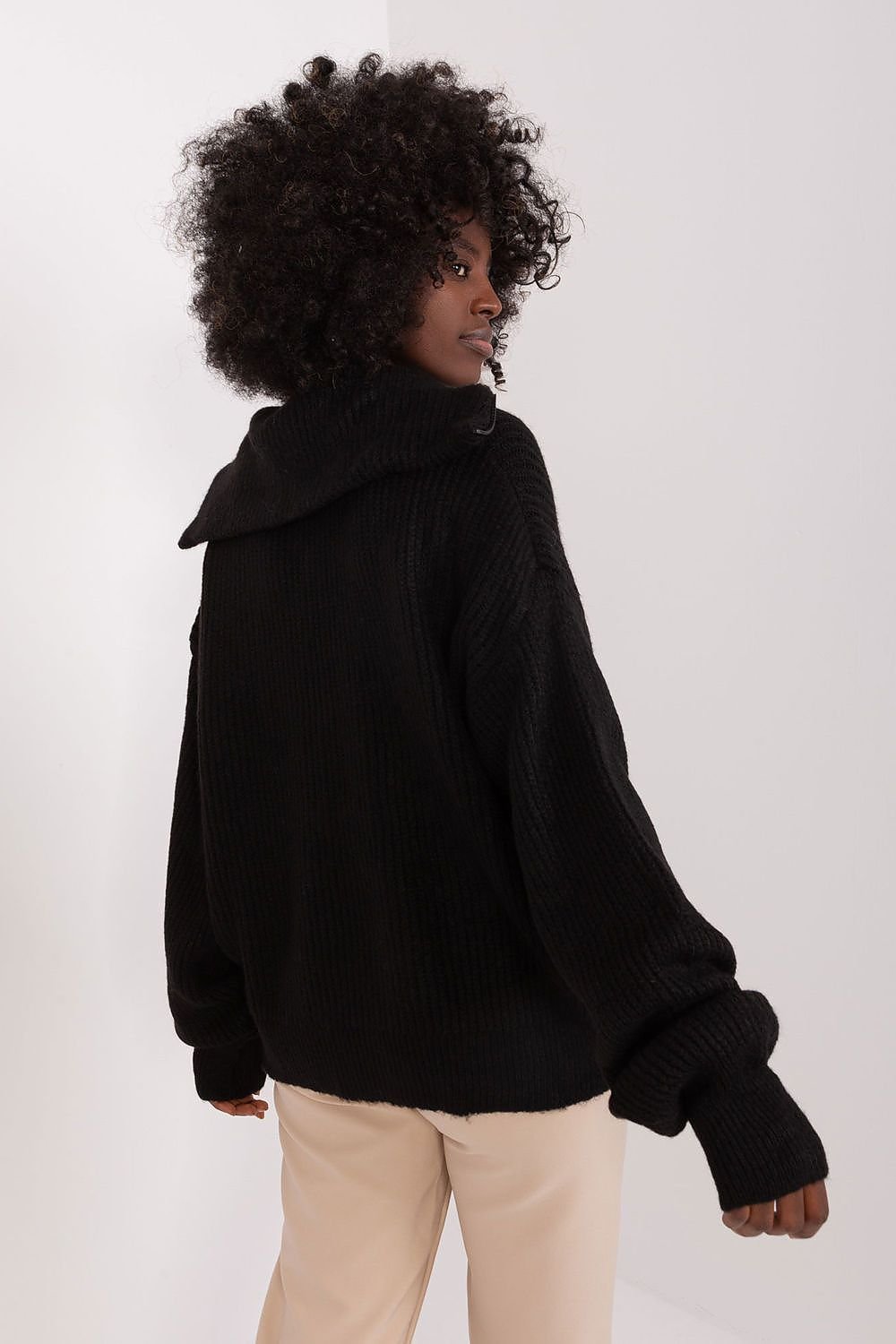 Curly-haired model wearing black turtleneck sweater