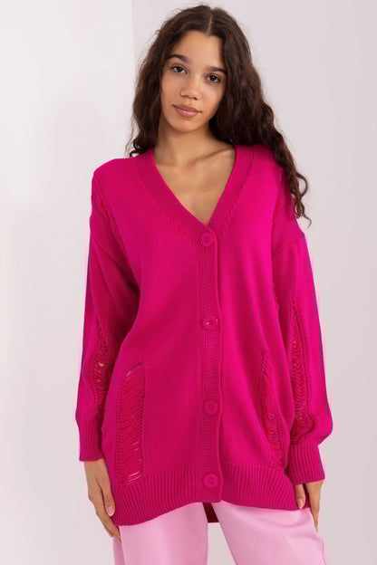 Vibrant fuchsia cardigan with oversized knitted design, worn by a smiling young woman with long dark hair.