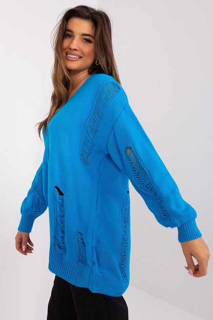 Bright blue textured knit cardigan with oversized fit and fraying detail, modeled by a smiling young woman with long brown hair.