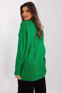 Green knit cardigan with round buttons on the front, worn by a smiling young woman with long brunette hair.