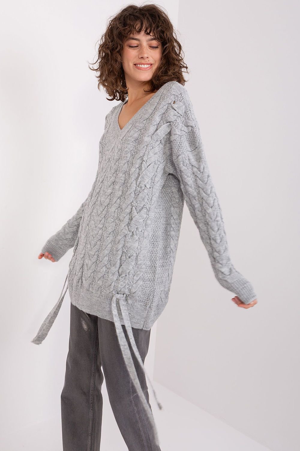 Elegant Knit Sweater Dress by Badu: Woman wearing a grey cable-knit sweater dress with a V-neck and long sleeves, showcasing a stylish and comfortable casual look.