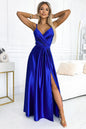 Elegant blue satin evening dress with high slit, worn by a young woman with blonde hair posing in a modern bedroom setting.