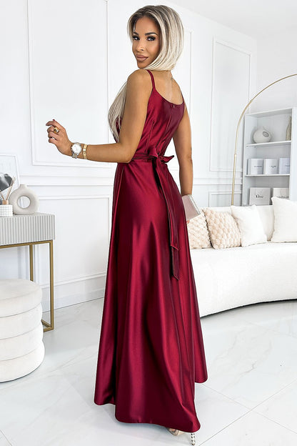 Elegant long dress by Numoco in deep red color, woman wearing the dress posing in stylish modern room setting