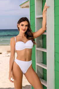 Elegant white two-piece swimsuit showcased on a beach near colorful cabana