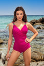 Vibrant magenta swimsuit one piece with beaded straps on woman posing by ocean