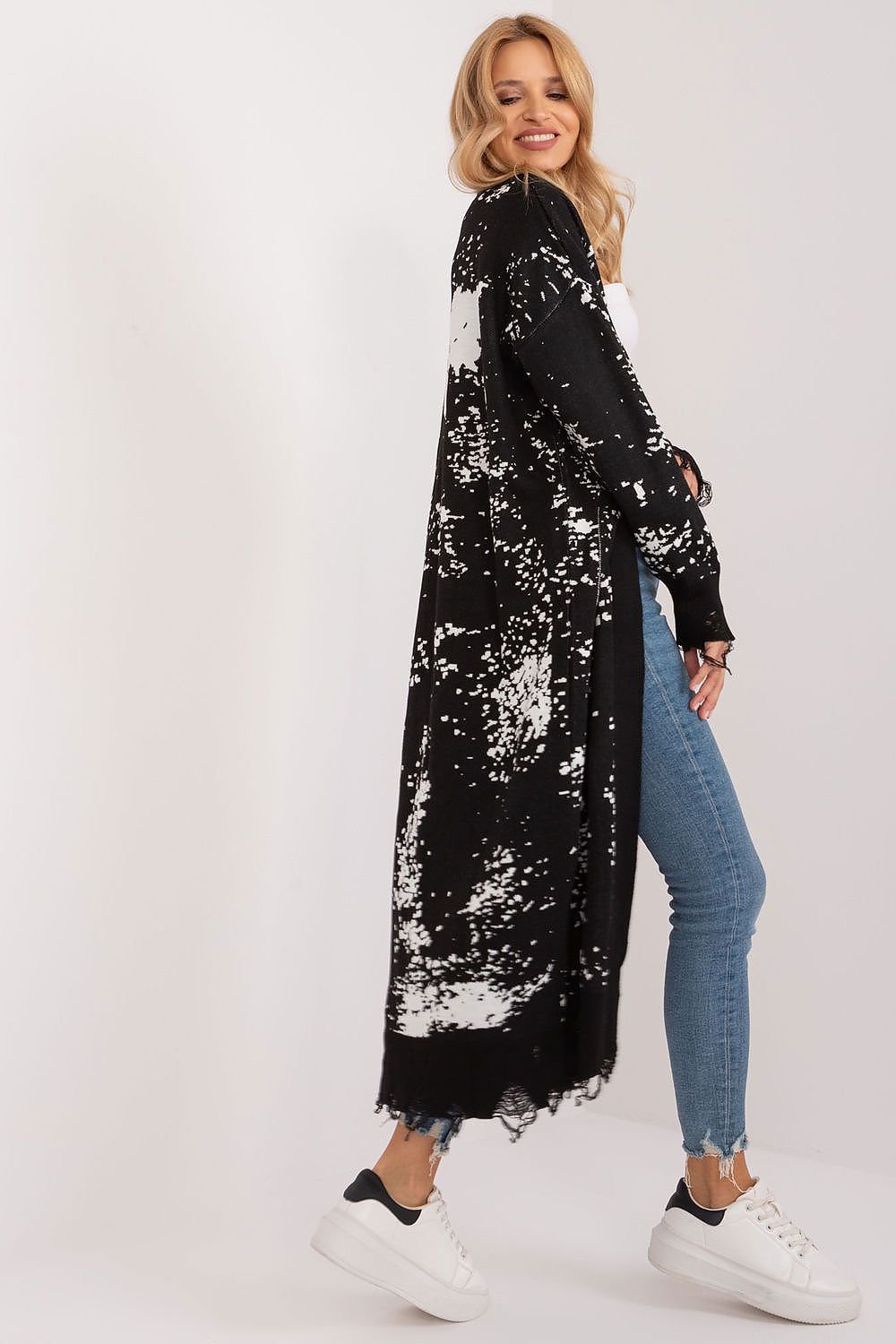 Elegant Floral Jacquard Maxi Cardigan in a stylish black and white pattern, worn by a smiling woman with blonde hair and casual outfitted in jeans and sneakers.