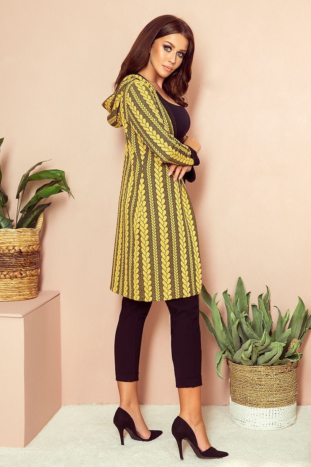 Stylish printed cardigan by Numoco, featuring a vibrant, eye-catching pattern and puff sleeves, worn by a fashionable young woman in a studio setting with potted plants.