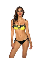 Load image into Gallery viewer, Stylish two-piece swimsuit with yellow top and black lace detailing, model with wavy dark hair posing on white background.