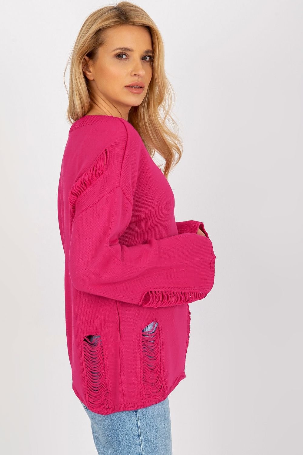 Vibrant pink oversized jumper with ruched details on the cuffs and hem, modeled by a young woman with long blonde hair in a white studio setting.