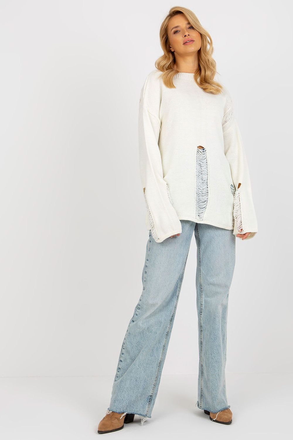 Cozy knit ivory jumper with bell sleeves, styled with relaxed light-wash denim jeans on a blonde woman against a plain background.