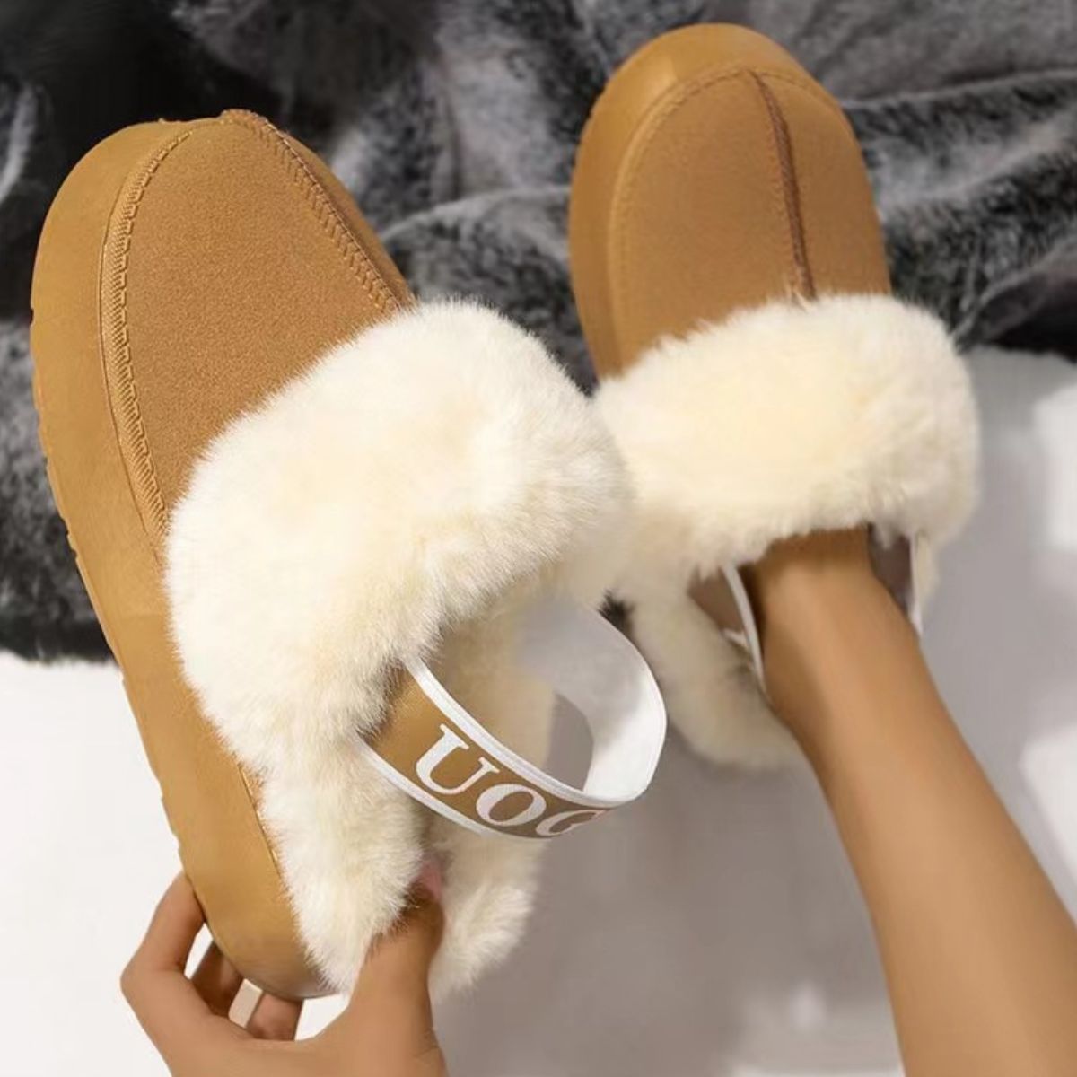 Plush tan suede platform slippers with cozy white fur trim and a decorative letter strap detail