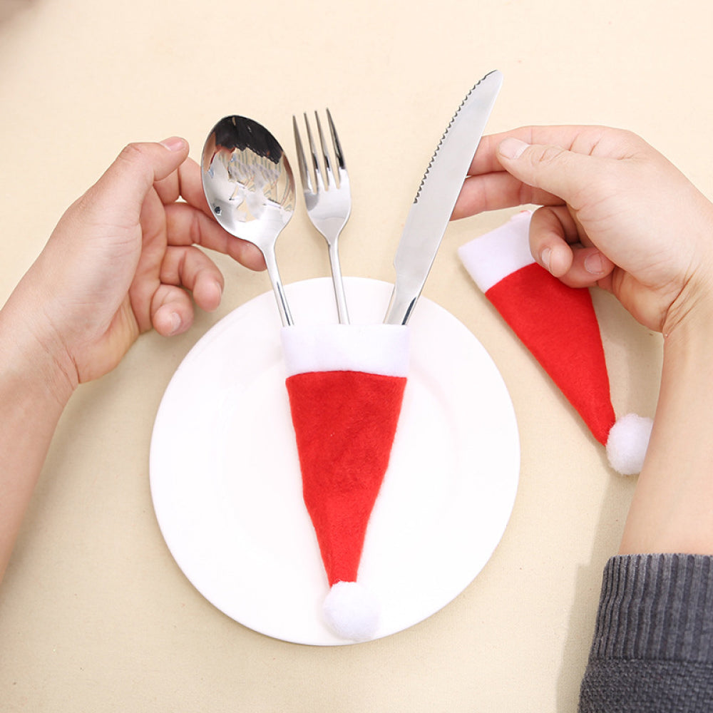 Christmas-themed cutlery holders in the shape of Santa hats, displayed on a white plate against a light background.