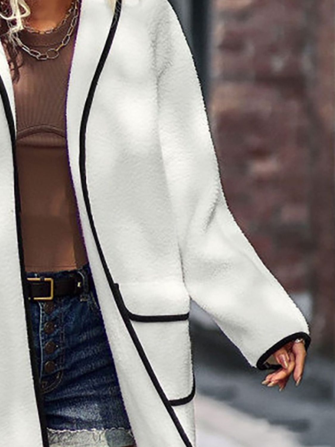 Cozy white faux fur long sleeve coat with contrast black trim and pockets, worn with jeans for a stylish casual look.