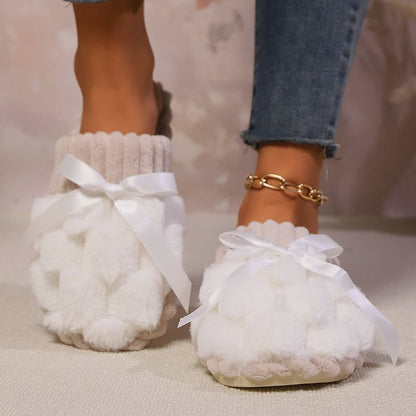 Cozy Bow-Trimmed Faux Fur Slippers
This image showcases a pair of soft, white faux fur slippers with decorative bows adorning the vamp. The slippers are worn by a person with jeans, highlighting their stylish yet comfortable design.