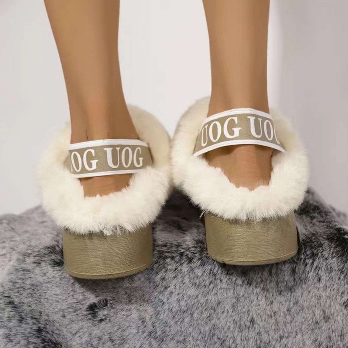 Cozy Platform Slippers with Plush Logo Straps
Soft, faux fur-lined platform slippers with a logo strap design, resting on a plush grey surface.