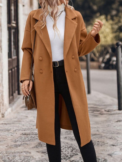 Chic camel-colored coat with dropped shoulders and a tie waist, showcased on a woman walking in a snowy urban setting.