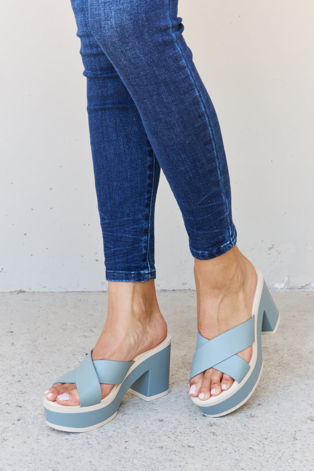 Misty blue platform sandals with a contrast design, worn with classic blue jeans on a neutral background.