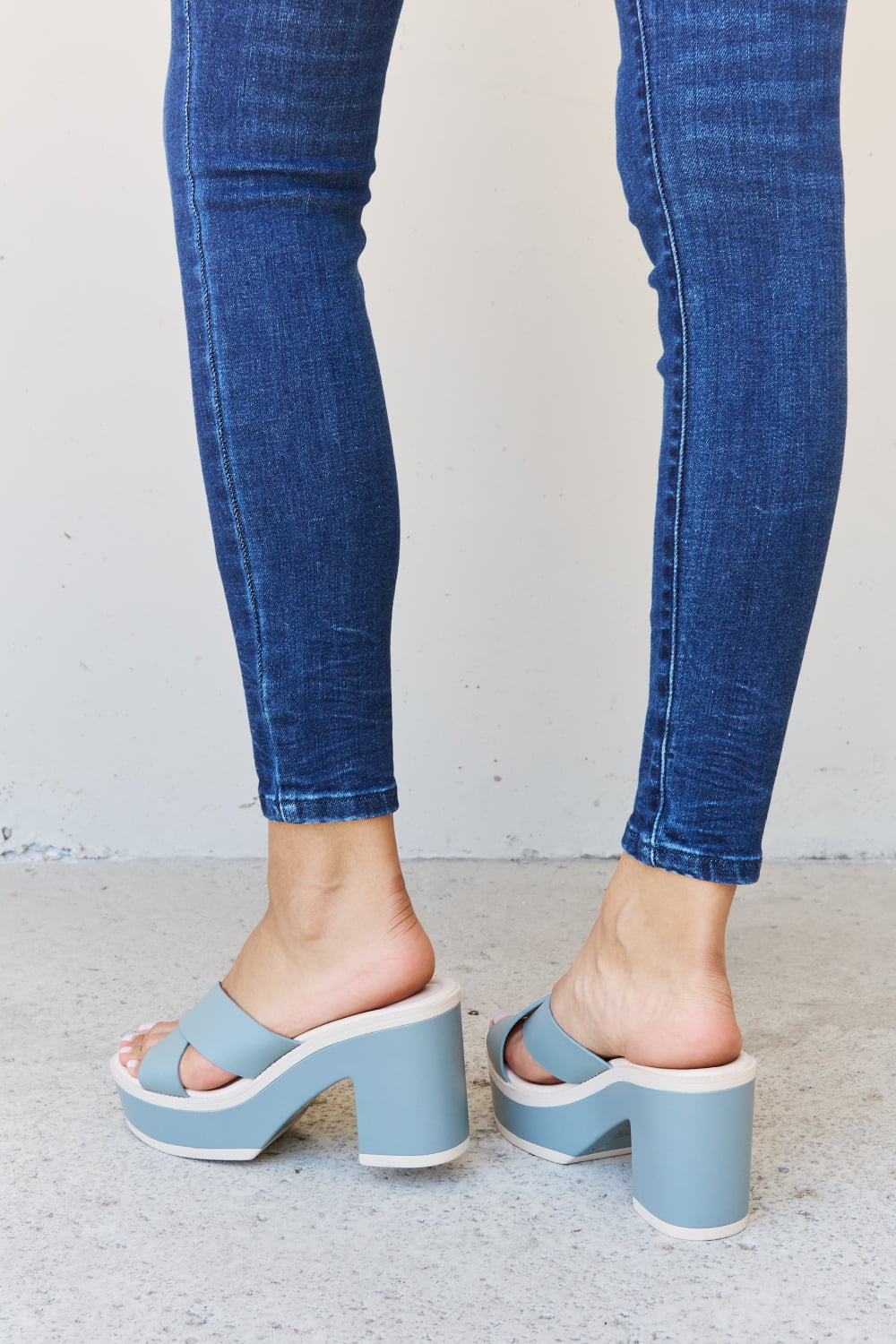 Stylish misty blue contrast platform sandals with a chunky heel, showcased with a pair of fashionable blue denim jeans.