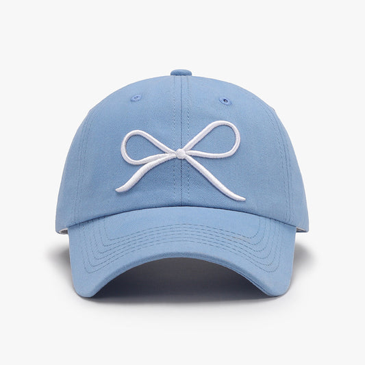 Stylish blue cotton baseball cap with embroidered white bow design, perfect accessory for fashionable casual wear.