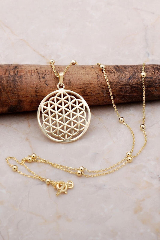 Elegant gold-plated flower of life pendant necklace on a wooden surface