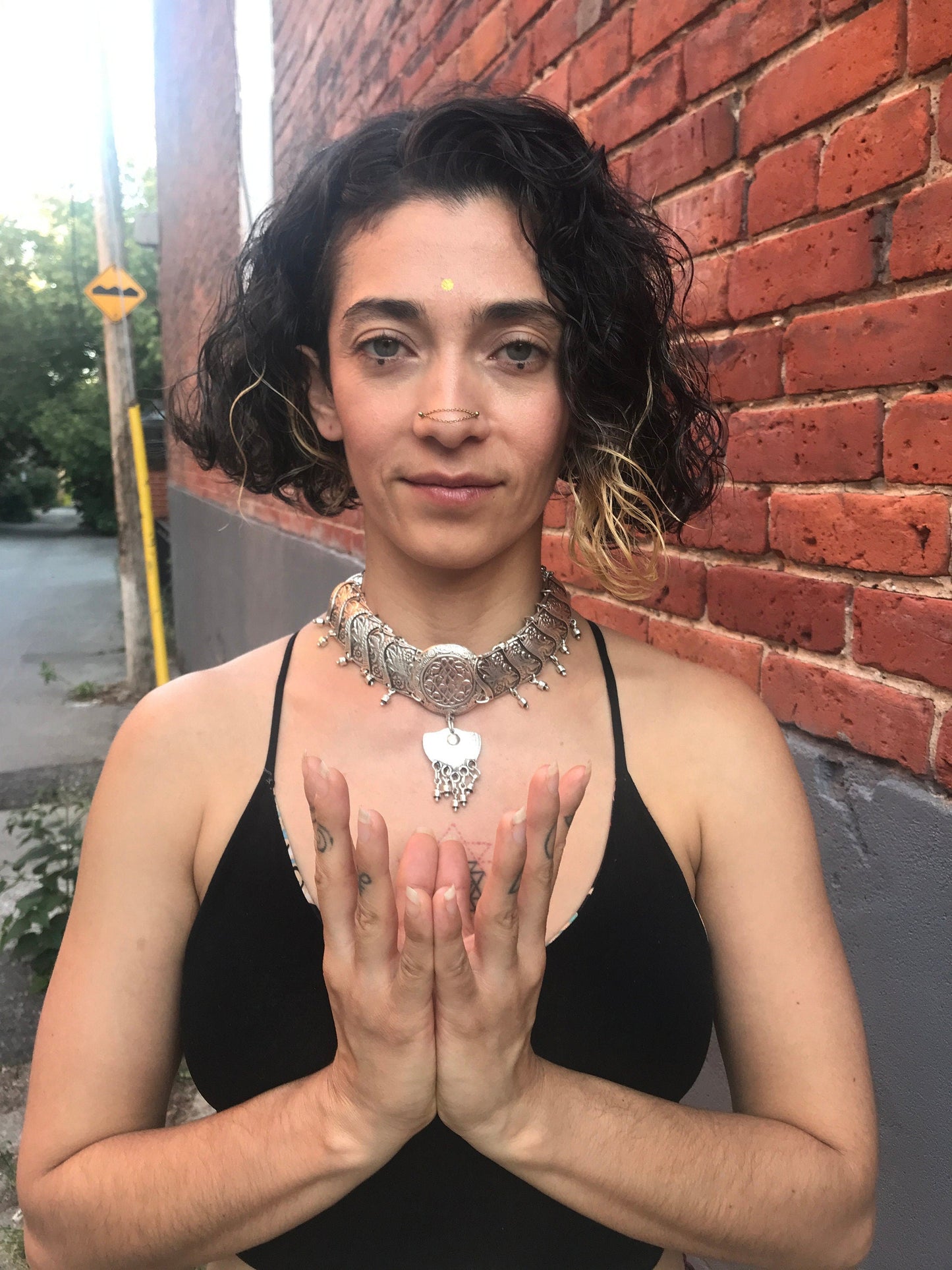 Elegant silver choker with heart charm on model in front of brick wall