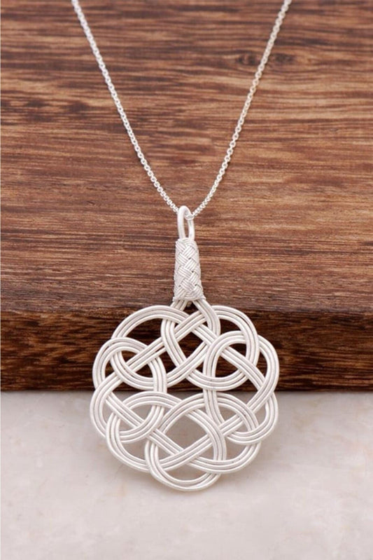 Stunning 1000 Sterling Silver Hand Wrapped Necklace on a wooden surface. The intricate, Celtic-inspired pendant features an elegant, woven design made from high-quality silver, creating a beautiful, eye-catching accessory for the modern, ethically-conscious fashionista.