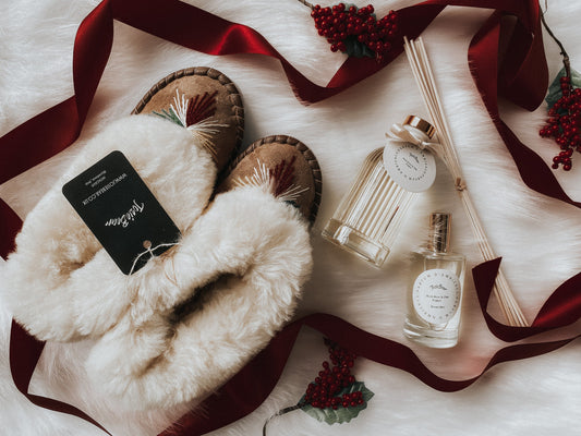 Cozy winter slippers, candles, and holiday decor - a luxurious gift set perfect for the stylish, conscious consumer.