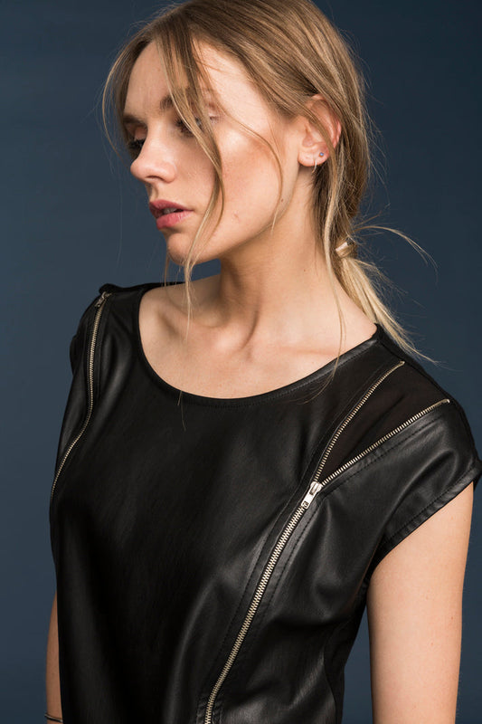 Sleek black leather front top with zipper details on the shoulders of a young woman against a dark background.